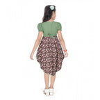 Young girl wearing a green floral layered asymmetrical dress with puff sleeves and stylish white flats