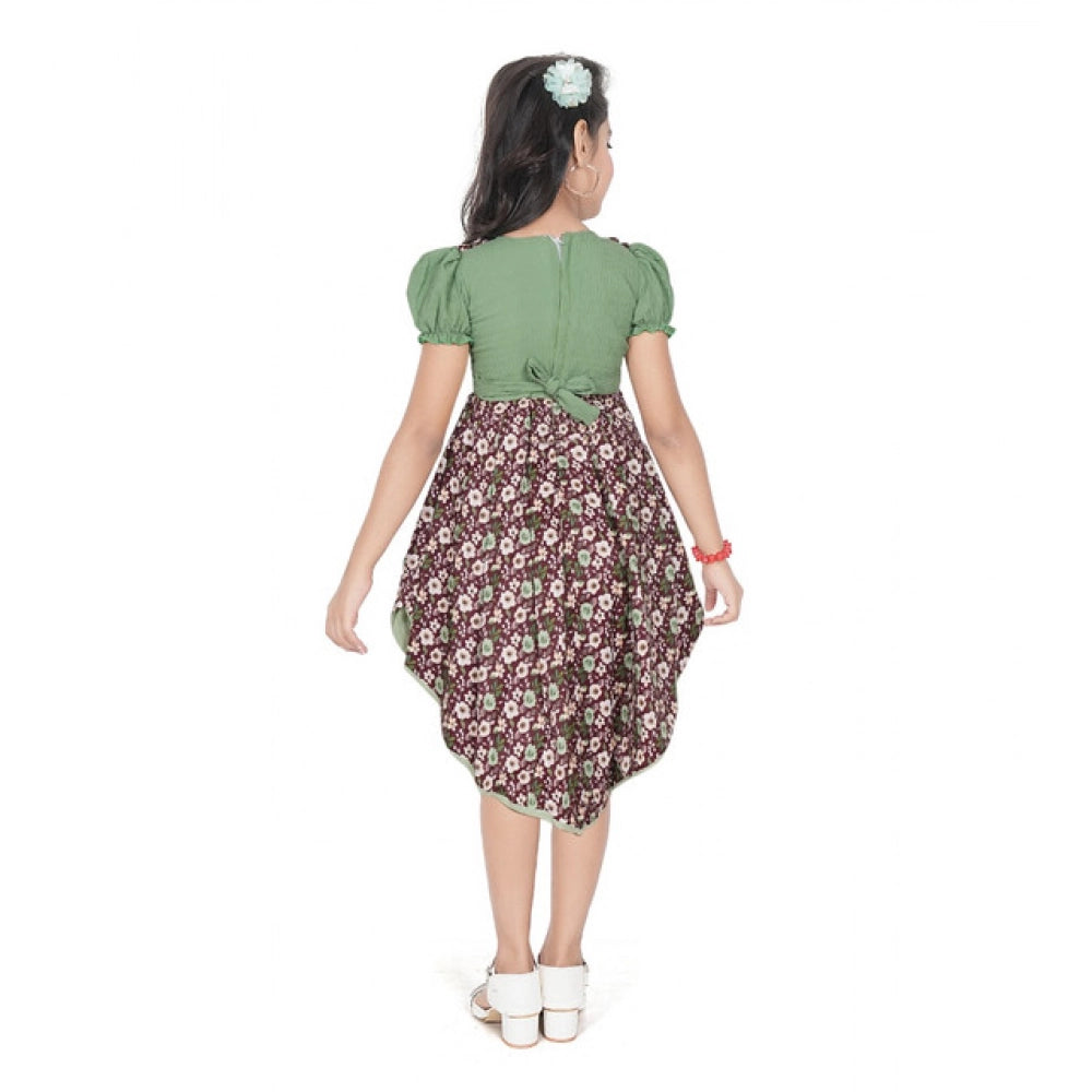 Young girl wearing a green floral layered asymmetrical dress with puff sleeves and stylish white flats