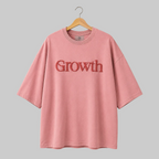 Pink t-shirt with 'Growth' text on a hanger against a gray background
