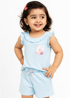 Child wearing a light blue outfit with a ruffled top and shorts on a white background