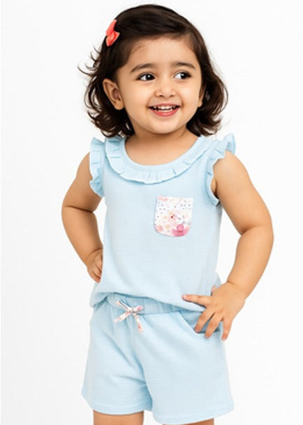 Child wearing a light blue outfit with a ruffled top and shorts on a white background