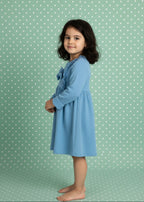 Young girl wearing a blue dress against a green polka dot background