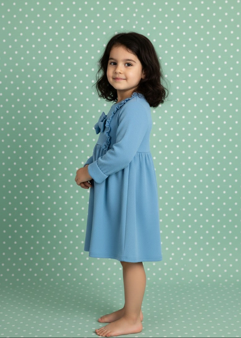 Young girl wearing a blue dress against a green polka dot background
