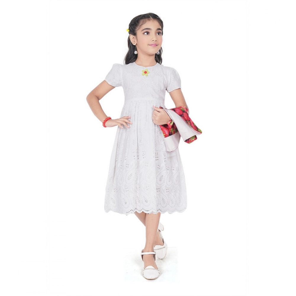 Young girl wearing a premium white eyelet dress layered with a vibrant strawberry print vest, perfect for festive or party wear