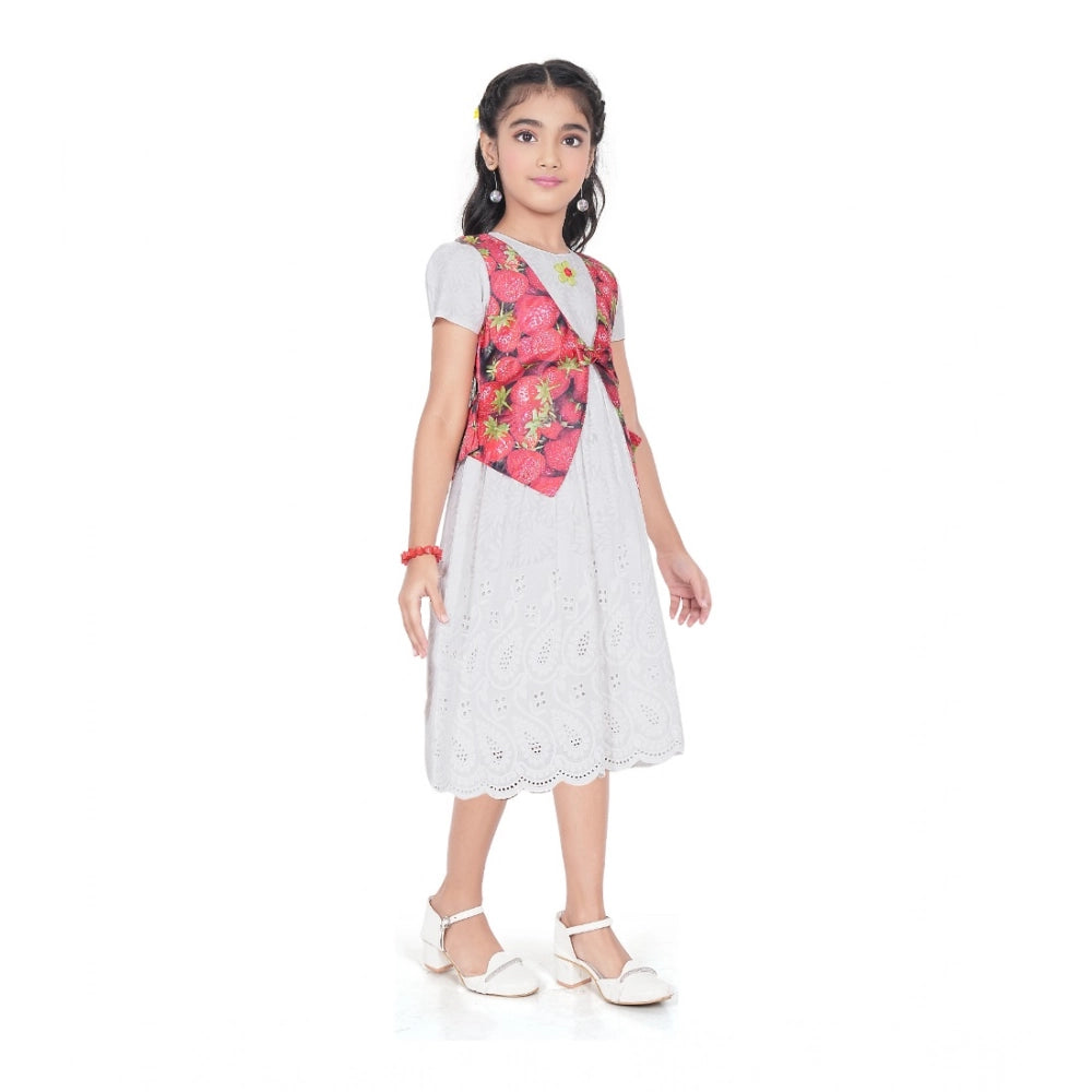 Young girl wearing a premium white eyelet dress layered with a vibrant strawberry print vest, perfect for festive or party wear